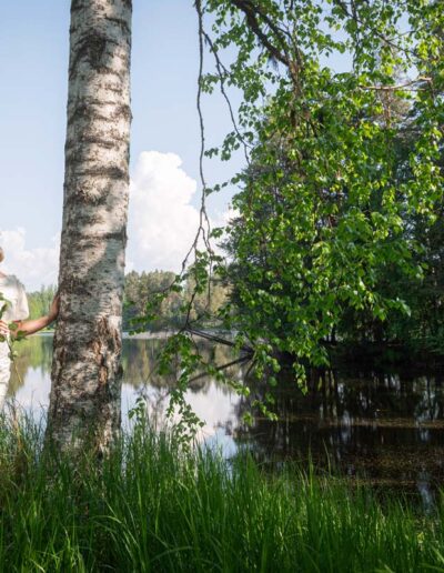 Ylioppilas nojaa koivuun rantakaislikossa.