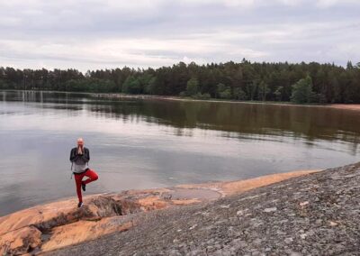 Mies seisoo yhdellä jalalla meren rantakalliolla.