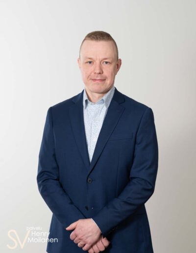 Mies poseeraa kameralle kädet ristissä.