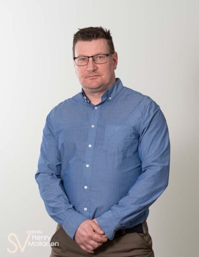 Mies poseeraa kameralle kädet ristissä.