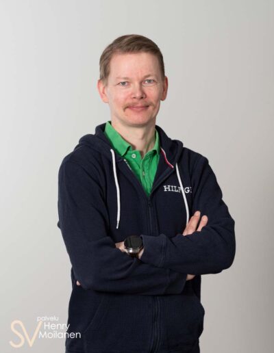 Mies poseeraa kameralle kädet puuskassa.