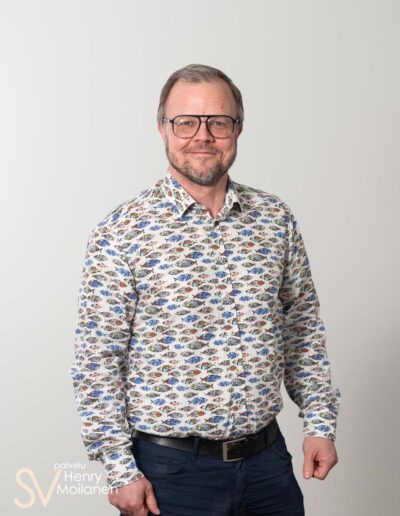 Mies poseeraa kameralle ja hymyilee.