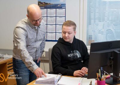 Kaksi miestä katsoo dokumentteja päätteen ääressä.