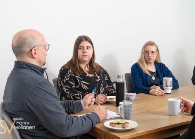 Kahvipöydässä istuvia ihmisiä.