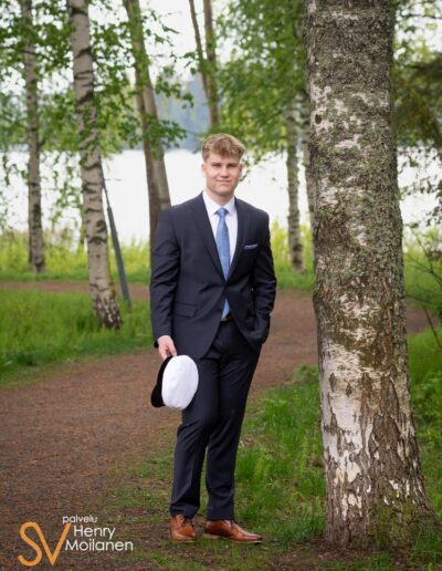 Ylioppilas seisoo lakki kädessään.