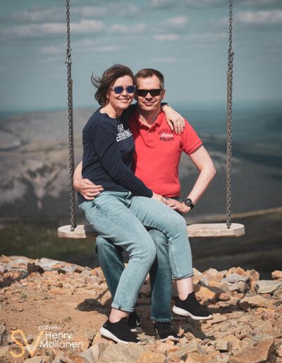 Nainen istuu miehen sylissä isossa keinussa lapissa.