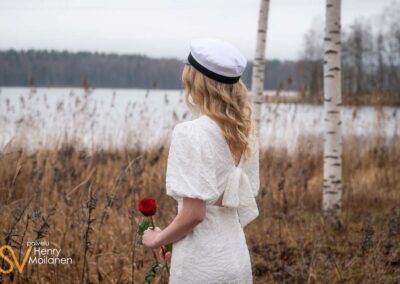 Ylioppilas katsoo järvelle ruusu kädessä.