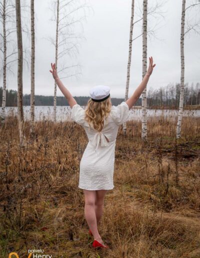 Ylioppilas tuulettaa koivikossa.