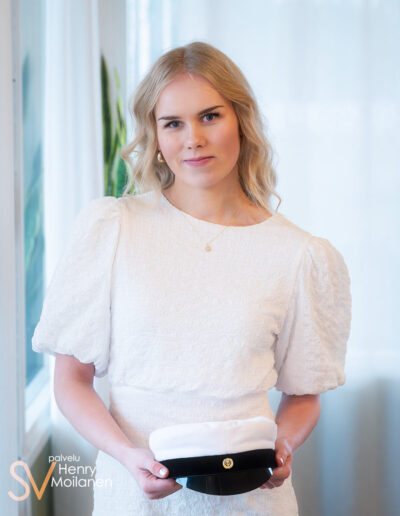 Ylioppilas pitää lakkia kaksin käsin.