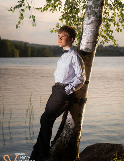 Poika nojaa koivuun rannalla.