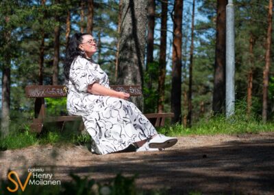 Nainen istuu penkillä silmät kiinni.