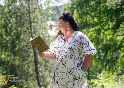 Nainen lukee kirjaa metsässä.