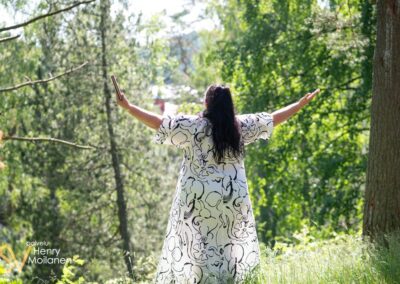 Nainen levittää kätensä puistossa.