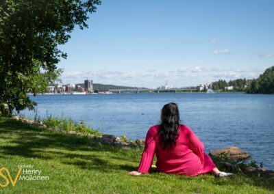 Nainen istuu nurmikolla järven rannassa Jyväskylässä.